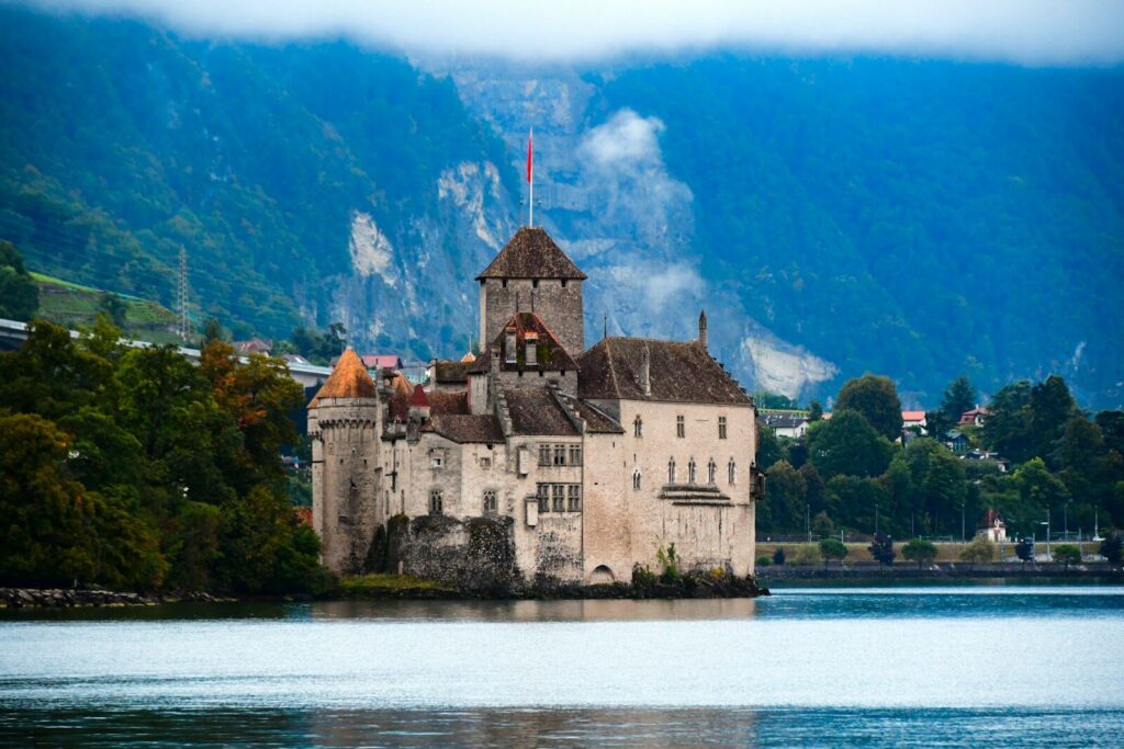 Home a castle sitting on top of a lake surrounded by mountains